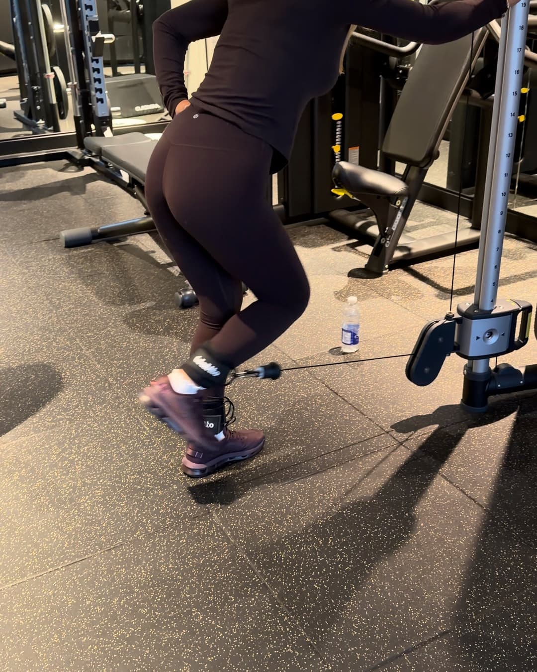 Une cliente effectue une extension de la jambe à la poulie dans la salle d'entraînement d'un immeuble.