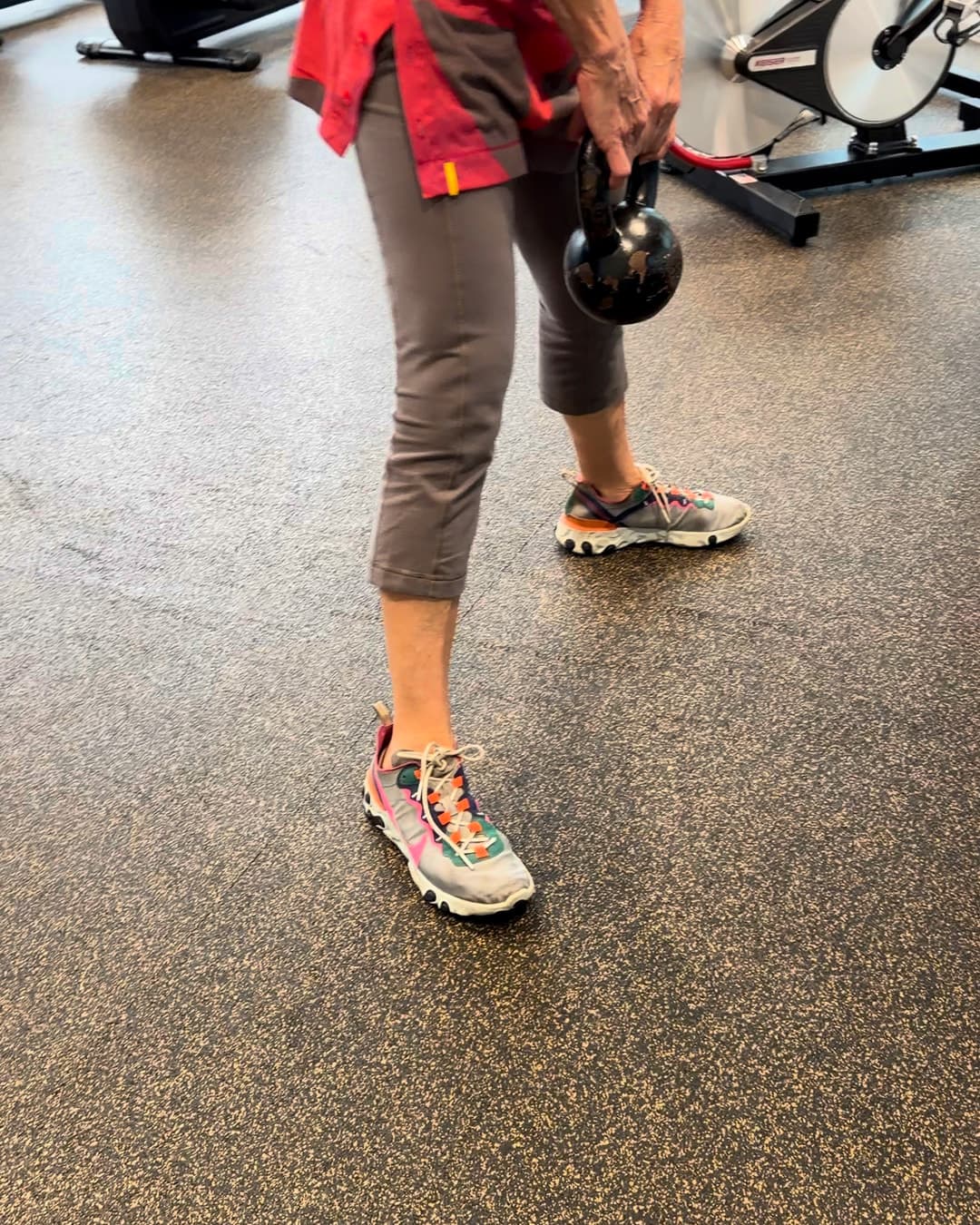 Une cliente effectue un soulevé de terre avec un kettlebell.